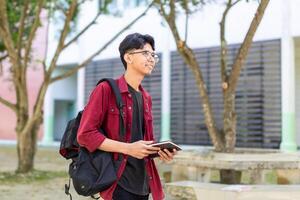 asiatisk högskola studerande läsning en bok på de campus parkera. foto