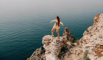 kvinna resa hav. Lycklig turist njut av tar bild utomhus för minnen. kvinna resande utseende på de kant av de klippa på de hav bukt av berg, delning resa äventyr resa foto