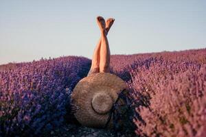 kvinna lavendel- fält. Lycklig sorglös kvinna ben pinne ut av de lavendel- buskar, värma solnedgång ljus. buskar av lavendel- lila i blomma, aromatisk blommor på lavendel- fält. foto