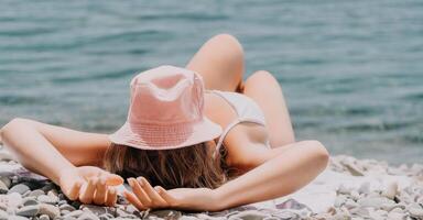 oigenkännlig positiv kvinna i vit bikini solbad eller garvning på havet strand under sommar. Lycklig turist njuter Sol solbränna liggande på strand stol vardagsrum på lyx tillflykt foto