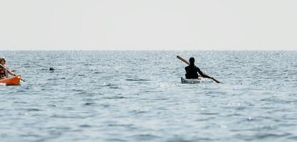 kvinna hav kajak. Lycklig leende kvinna i kajak på hav, paddling med trä- åra. lugna hav vatten och horisont i bakgrund. aktiva livsstil på hav. sommar semester. foto