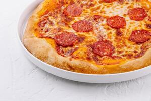 nyligen bakad pepperoni pizza på vit tallrik foto