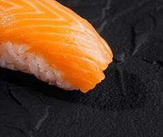 färsk lax nigiri sushi på svart skiffer foto