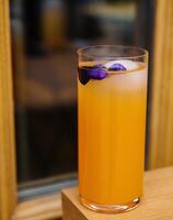 uppfriskande orange cocktail med ätlig blomma garnering foto