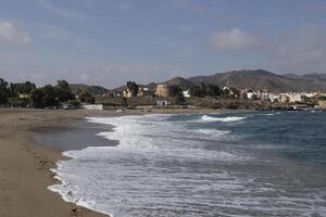 bukt av villaricos, grov hav, strand, by och bergen på de bakgrund foto