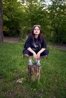 en Tonårs flicka i svart kläder i grunge stil foto