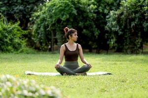 Söt varm kvinna Sammanträde utomhus i yoga utgör foto