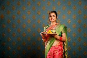 Söt hemmafru i saree innehav diya tallrik under de diwali firande foto