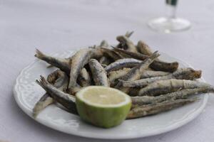 boquerones eller friterad sardiner på en tallrik med citron, skaldjur i Spanien foto