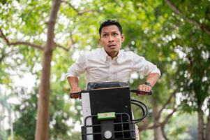ett angelägen asiatisk affärsman är i en skynda till skaffa sig till arbete i de morgon, ridning en cykel. foto