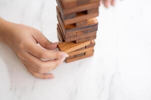 en kvinna betalar henne uppmärksamhet på spelar en trä- blockera spel på en tabell, rör på sig en trä- blockera. foto