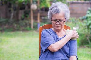 en senior kvinna har axel smärta användningar en thai ört- komprimera boll på de axel. ett gammal kvinna vem har problem med henne axel Maj orsak förbi en muskel anstränga. sjukvård begrepp foto