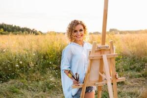 Söt kvinna är målning. öppen luft session. söt kvinna drar en bild på solnedgång. flicka konstnär. foto