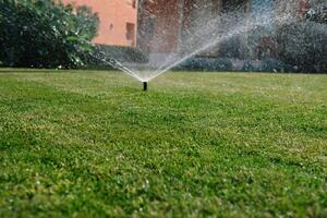 modern enhet av bevattning trädgård. bevattning systemet - Metod av vattning i de trädgård. gräsmatta sprinkler besprutning vatten över grön gräs. foto