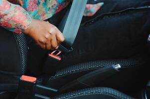 mörk brun hud afrikansk kvinna hand knäckning säkerhet bälte i de bil för bil olycka säkerhet begrepp foto