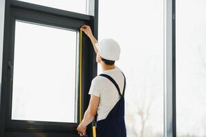 manlig industriell byggare arbetstagare på fönster installation i byggnad konstruktion webbplats foto