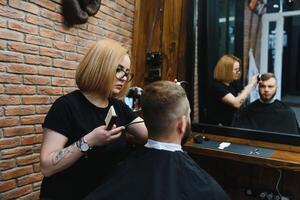 eleganta man Sammanträde barberare affär hårstylist frisör kvinna skärande hans hår porträtt stilig Lycklig ung skäggig caucasian kille få trendig frisyr attraktiv barberare flicka arbetssätt tjänande klient. foto