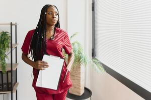 porträtt av skön leende kvinna afrikansk amerikan läkare stående i medicinsk kontor. hälsa vård begrepp, medicinsk försäkring, kopia Plats foto