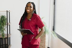 porträtt av skön leende kvinna afrikansk amerikan läkare stående i medicinsk kontor. hälsa vård begrepp, medicinsk försäkring, kopia Plats foto