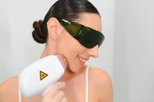 närbild av kosmetolog ger epilering laser behandling på kvinnas ansikte foto
