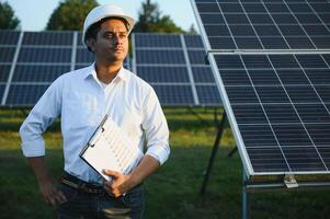 porträtt ung indisk tekniker eller chef bär formell torkdukar stående med sol- panel. förnybar energi, man stående korsade ärm, kopia Plats foto