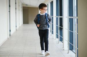 skol med skolväska och böcker i de skola. utbildning begrepp. tillbaka till skola. schoolkid gående till klass. eleganta pojke med ryggsäck. pojke redo till studie. foto