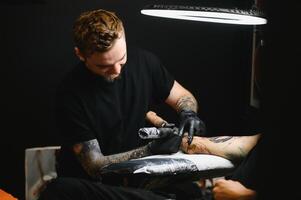 tatuerare med hans maskin tatuering på de ärm med de design ritade, begrepp av konst och design foto