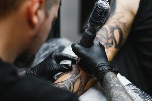 tatuerare med hans maskin tatuering på de ärm med de design ritade, begrepp av konst och design foto