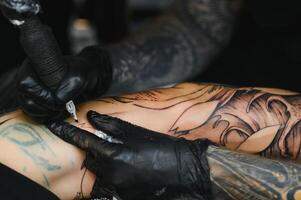 tatuerare med hans maskin tatuering på de ärm med de design ritade, begrepp av konst och design foto
