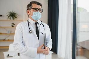 manlig läkare med medicinsk ansikte mask och en stetoskop på klinik foto