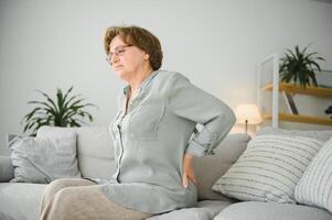 gammal ålder, hälsa problem och människor begrepp - senior kvinna lidande från smärta i tillbaka eller tyglar på Hem foto