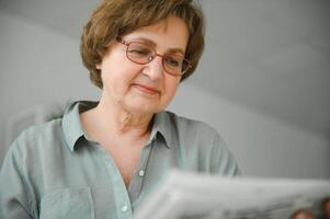 ålder och människor begrepp - Lycklig senior kvinna läsning tidning på Hem foto