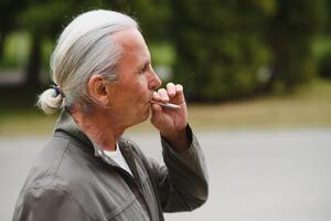 ett gammal senior man rökning cigarett utanför, rök missbruk, dålig habbit foto
