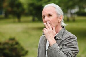 ett gammal senior man rökning cigarett utanför, rök missbruk, dålig habbit foto