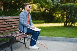 blind man läsning bok på bänk i parkera foto