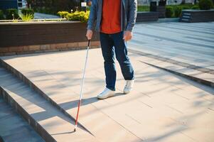 närbild av en blind man stående med vit pinne på gata foto
