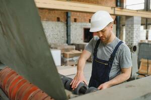 arbetstagare i skyddande Kläder i fabrik använder sig av maskin foto