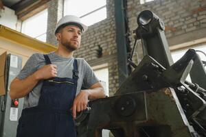 arbetstagare i skyddande Kläder i fabrik använder sig av maskin foto