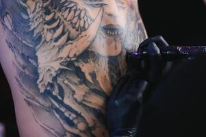 tatuering konstnär händer bär handskar och innehav en tatuering maskin foto
