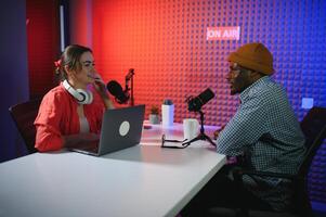 två radio värdar i hörlurar skrattande medan inspelning podcast i studio tillsammans foto
