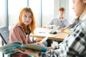 Lycklig grupp av vänlig studenter talande, diskuterar ny skola projekt idéer tillsammans foto