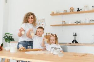 familj inlärning ny recept tillsammans. Lycklig mamma och barn blandning Ingredienser för hemlagad kaka, paj eller kaka deg i de kök. foto