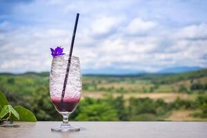 främre se av en glas av iced blandad bär soda på trä- tabell med natur bakgrund. begrepp av kall dryck och resa foto