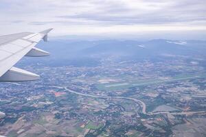 antenn se av jordbruks fält, flod, berg, och moln är sett genom de flygplan fönster foto