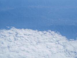 Flygfoto över land och moln sett genom flygplansfönster foto
