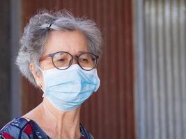 porträtt av ett äldre kvinna bär en kirurgisk mask med en orolig. mask för skyddande virus, coronavirus, covid19, pollen korn, och Mer. begrepp av åldrig människor och sjukvård foto