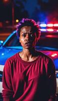 Foto av porträtt stänga upp se av kriminell misstänka i brottslighet scen stående i främre av polis bil på natt och röd blå ljus,
