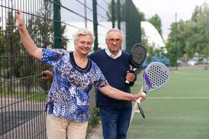 porträtt av sportig passa senior kvinna spelar padel på öppen domstol på sommar dag, redo till träffa boll. hälsa och aktiva livsstil begrepp.. foto