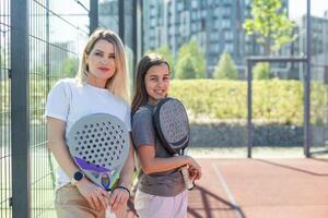 skön flickor få redo för en träna på de padel tennis domstol foto