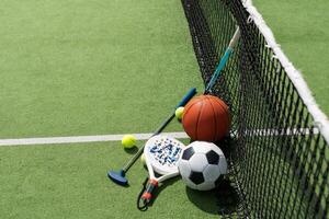 fotboll fotboll boll basketboll tennis boll och racket lagd på gräs på solnedgång foto